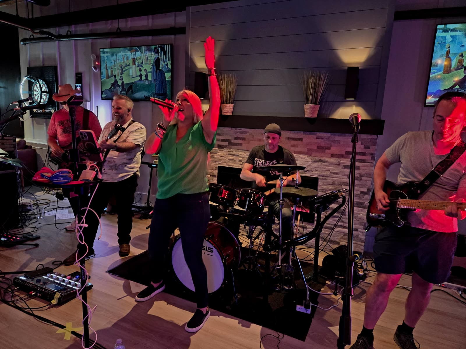 Lead singer with arm raised, band performing under red stage lights